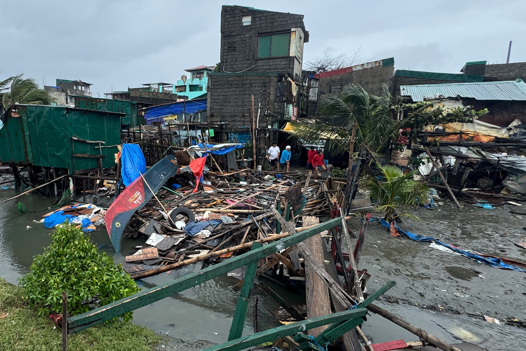 Residents stand beside a damaged house and toppled bridge due to Typhoon Fung-wong along a coastal village on Monday, Nov. 10, 2025, in Navotas, Philippines. (AP Photo/Aaron Favila)