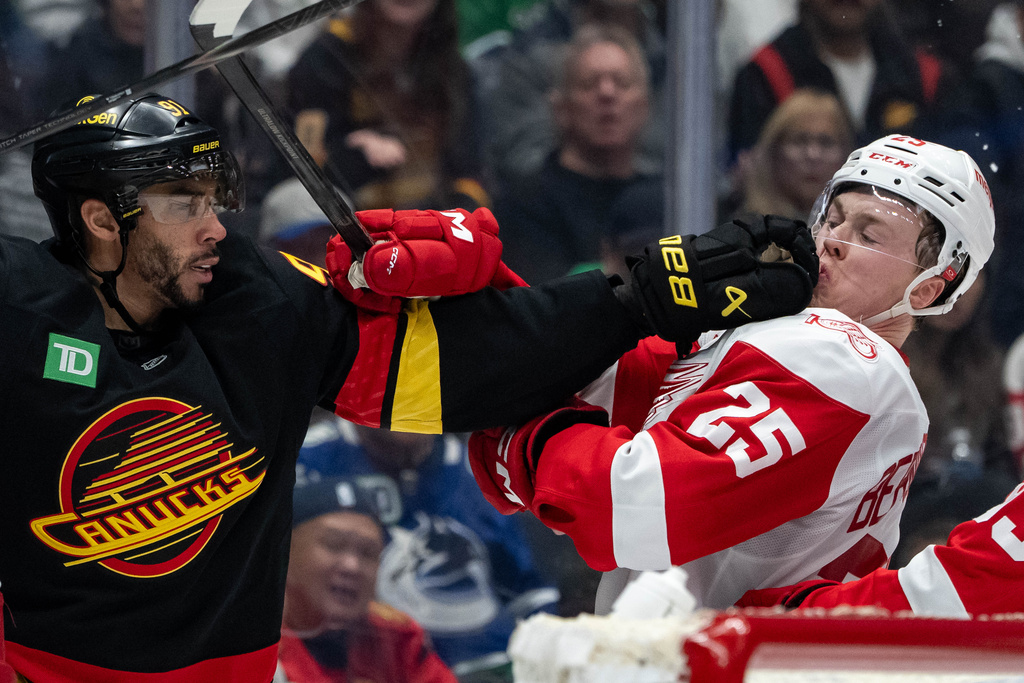 Vancouver Canucks' Evander Kane (91) punches Detroit Red Wings' Jacob Bernard-Docker (25) during the third period of an NHL hockey game in Vancouver, B.C., Monday, Dec. 8, 2025. (Ethan Cairns/The Canadian Press via AP)