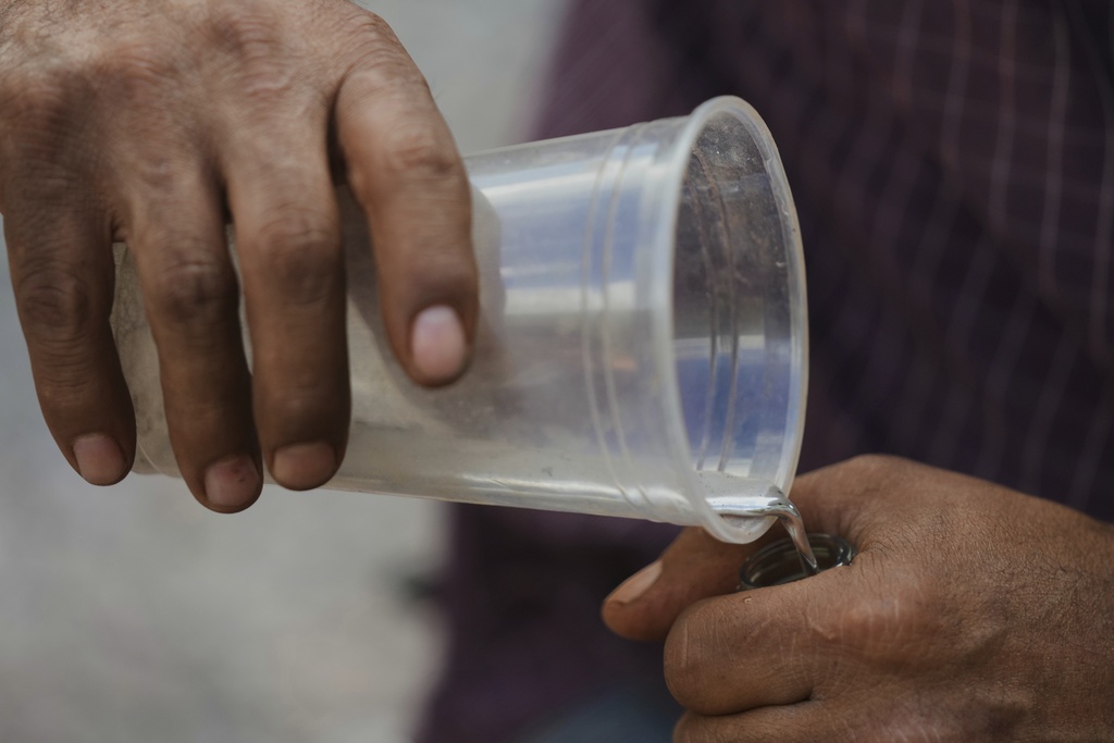 A miner transfers a sample of mercury into a Coca-Cola bottle in San Joaquin, Mexico, Tuesday, Aug. 19, 2025. (AP Photo/Fernando Llano)