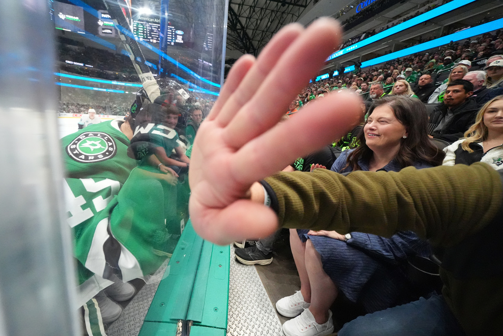 A spectator bangs on the glass as Dallas Stars center Justin Hryckowian (49) competes for possession of the puck agains Seattle Kraken center Ryan Winterton, not visible, during the first period of an NHL hockey game Sunday, Nov. 9, 2025, in Dallas. (AP Photo/Julio Cortez)
