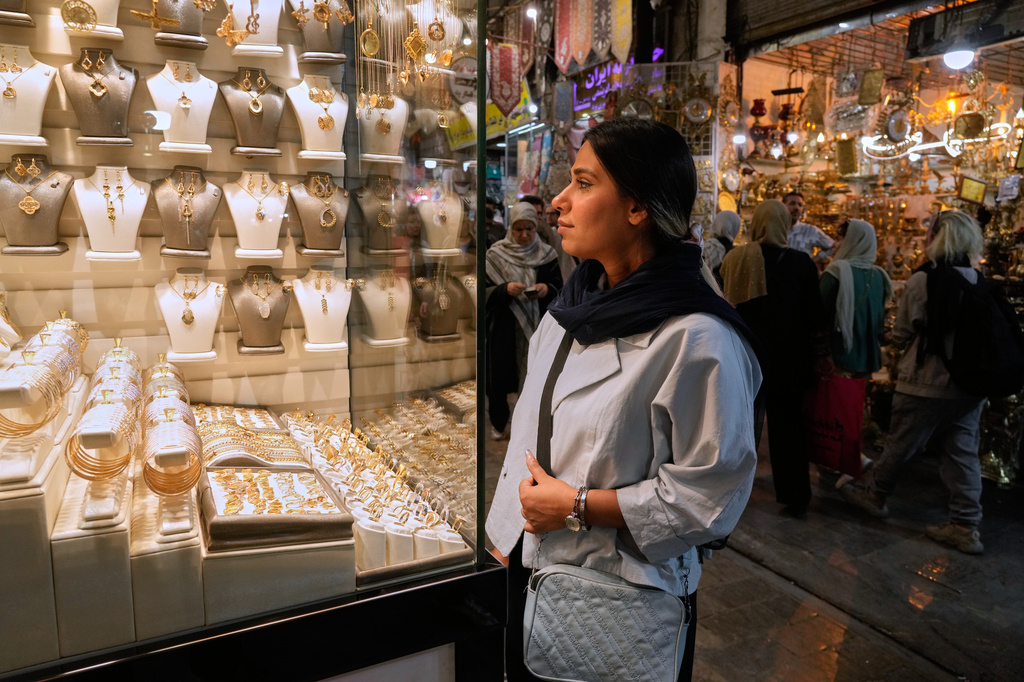 A woman looks at jewelry in the window of a gold shop at Tehran's historic Grand Bazaar, Iran, Sunday, May 3, 2026. (AP Photo/Vahid Salemi)