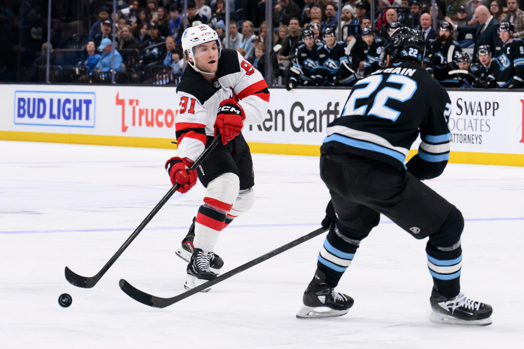 New Jersey Devils center Dawson Mercer (91) passes the puck past Utah Mammoth center Jack McBain (22) during the second period of an NHL hockey game, Friday, Dec. 19, 2025, in Salt Lake City. (AP Photo/Tyler Tate)