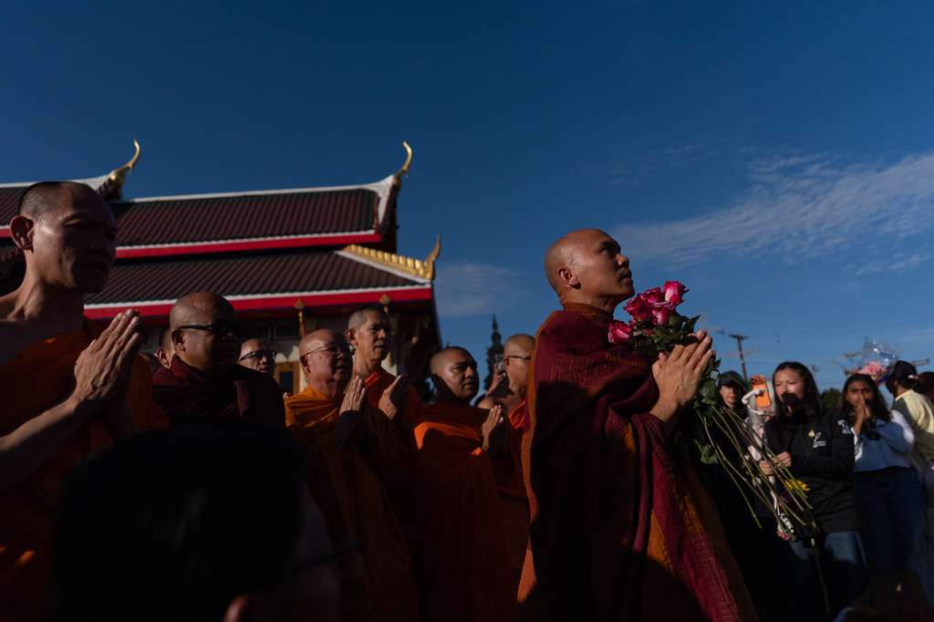 Bhikkhu Pannakara, foreground right, a Buddhist monk who led a Walk for Peace from Fort Worth, Texas, to Washington, D.C., carries flowers as he pays his respects at a monument during an event at Wat Thai of Los Angeles in the North Hollywood section of Los Angeles, Monday, July 13, 2026. (AP Photo/Jae C. Hong)