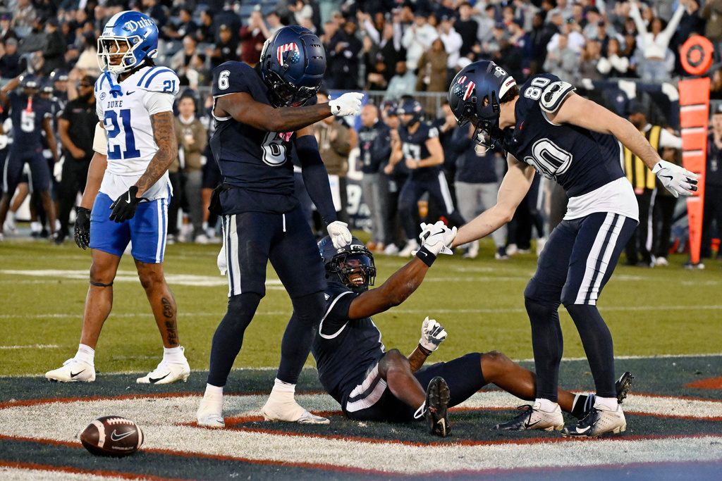 UConn wide receiver John Neider (80) helps teammate Skyler Bell (1) up after Bell scored a touchdown as teammate Reymello Murphy (6) celebrates during the first half of an NCAA college football game against Duke, Saturday, Nov. 8, 2025, in East Hartford, Conn. (AP Photo/Jessica Hill)