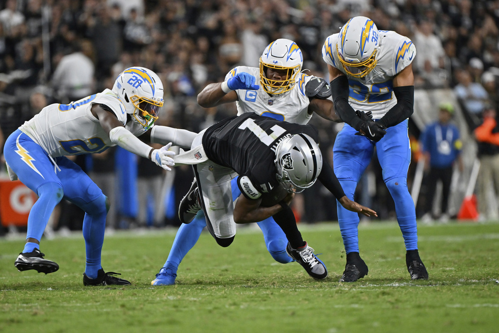 Los Angeles Chargers cornerback Cam Hart (20) tackles Las Vegas Raiders quarterback Geno Smith (7) during the first half of an NFL football game, Monday, Sept. 15, 2025, in Las Vegas. (AP Photo/David Becker)