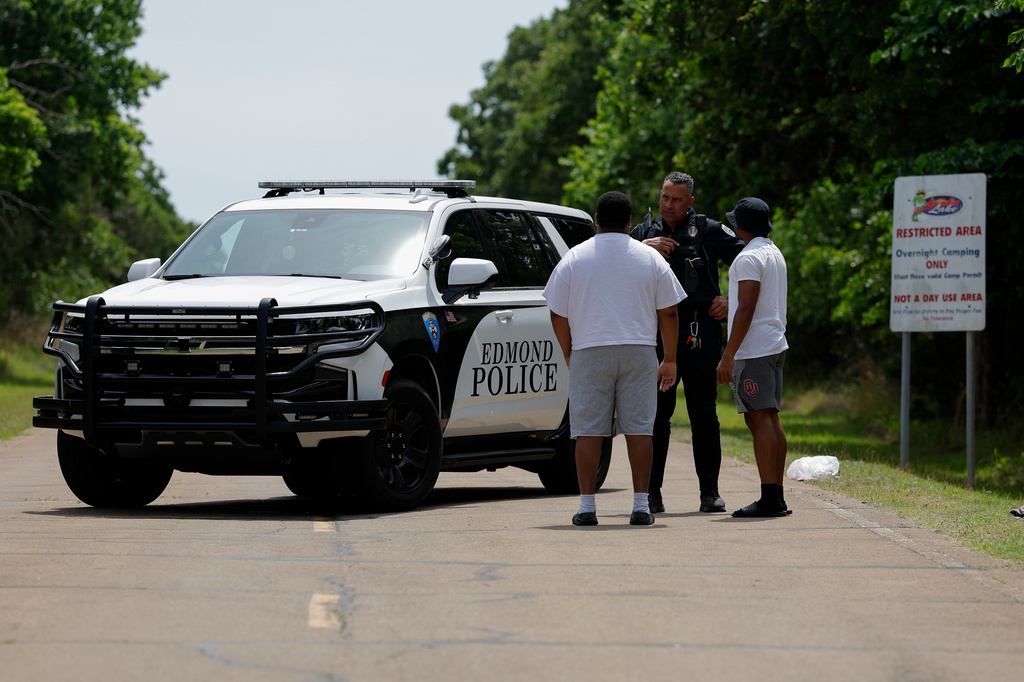 Police talks to two guys at the entrance to Scissortail Campground at Arcadia Lake in Edmond, Okla. who are wanting to get their belongings from the campground on Monday, May 4, 2026 after a party shooting on Sunday evening. (AP Photo/Alonzo Adams)