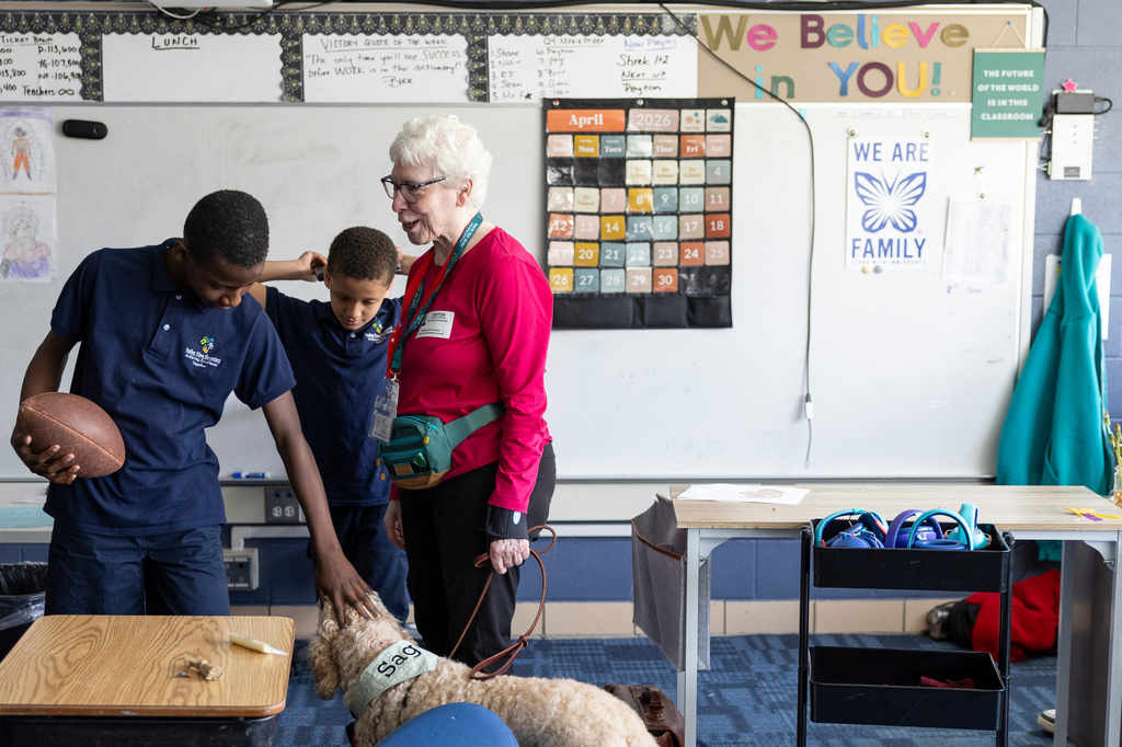 Shane Jackson, left, pets Sage, a therapy dog, while chatting with Sage's owner, Linda Buchs-Hammonds, at Valley View Elementary School on April 29, 2026, in Columbia Heights, Minn. (Ellen Schmidt/MinnPost via AP)