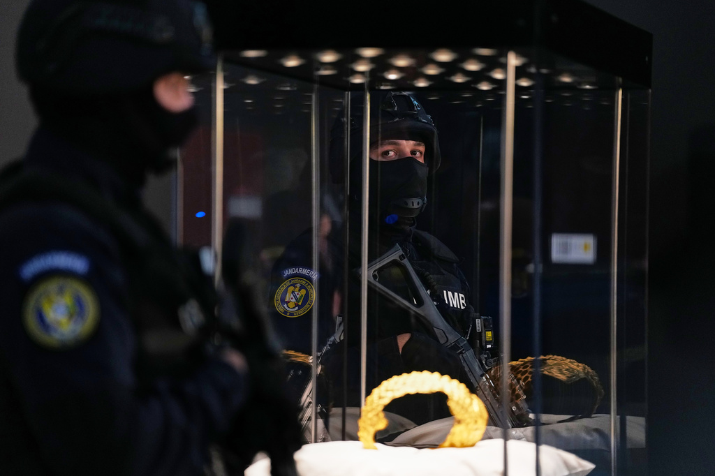 Armed gendarmes stand by Dacian gold items, a 2,500-year-old helmet and wristbands, stolen from a museum in the Netherlands and then recovered by Dutch authorities, during a press conference after being returned, at the National Museum of Romanian History, in Bucharest, Romania, Tuesday, April 21, 2026. (AP Photo/Andreea Alexandru)