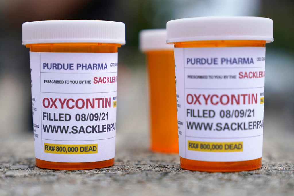 FILE - Fake pill bottles with messages about OxyContin maker Purdue Pharma are displayed during a protest outside the courthouse where the bankruptcy of the company is taking place in White Plains, N.Y., on Aug. 9, 2021. (AP foto/Seth Wenig, File)