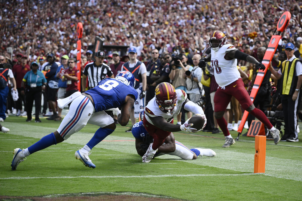 Washington Commanders wide receiver Deebo Samuel (1) diving in to score a touchdown against New York Giants safety Jevon Holland (8) during the second half of an NFL football game, Sunday, Sept. 7, 2025, in Landover, Md. (AP Photo/Nick Wass)