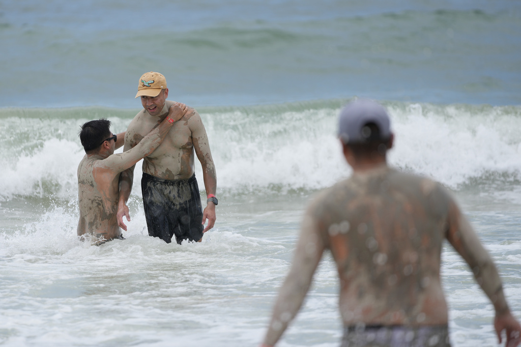 Visitors who are covered in mud during the Boryeong Mud Festival play at a beach in Boryeong, South Korea, Saturday, July 25, 2026. (AP Photo/Lee Jin-man)