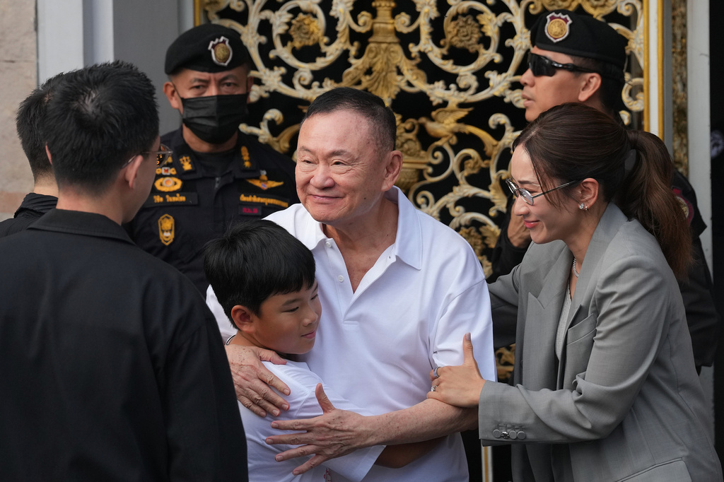 Former Thailand Prime Minister Thaksin Shinawatra hugs his grandson with his daughter Pinthongta Shinawatra, right, following his release on parole from a Bangkok prison in Bangkok, Thailand, Monday, May 11, 2026. (AP Photo/Sakchai Lalit)