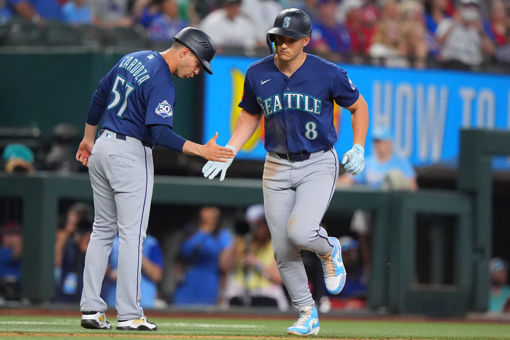 Seattle Mariners designated hitter Dominic Canzone (8) is congratulated by third base coach Carlos Cardoza, left, after hitting a home run during the seventh inning of a baseball game against the Texas Rangers, Sunday, July 26, 2026, in Arlington, Texas. (AP Photo/LM Otero)