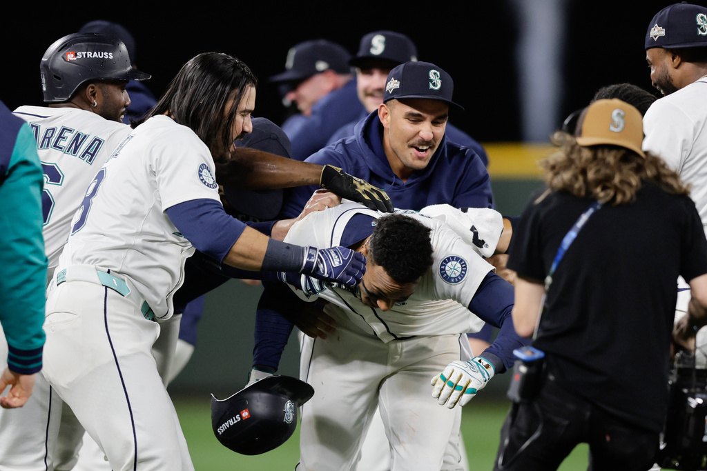 Seattle Mariners players celebrate with Jorge Polanco, center, after he hit the game-winning RBI single in the 15th inning in Game 5 of baseball's American League Division Series against the Detroit Tigers, Friday, Oct. 10, 2025, in Seattle. (AP Photo/John Froschauer)