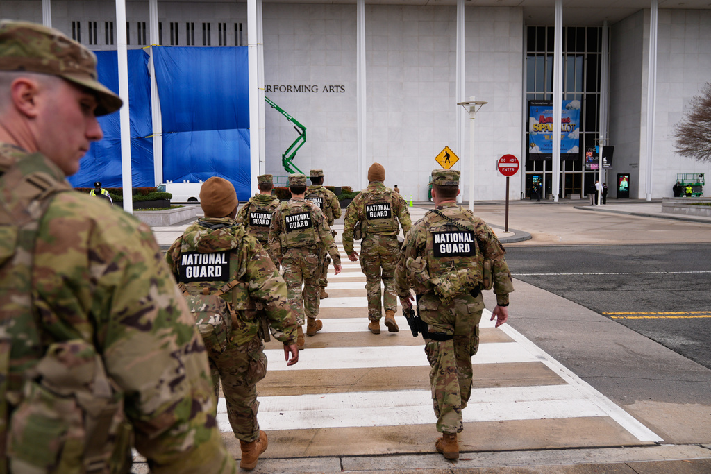 National Guard soldiers walk toward the Kennedy Center as work is done on the signage on the exterior of Kennedy Center, Friday, Dec. 19, 2025, in Washington. (AP Photo/Mark Schiefelbein)