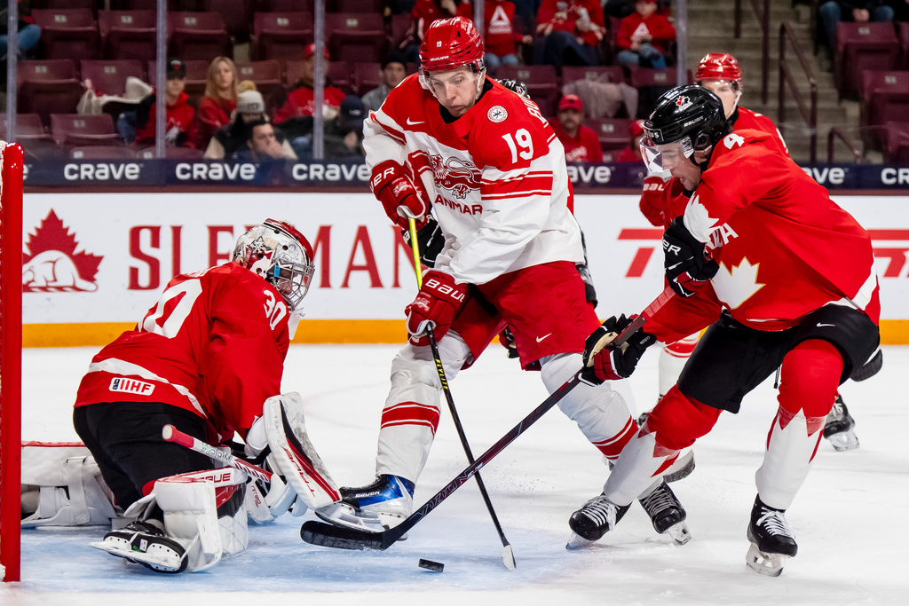 Canada goaltender Carter George (30) and Harrison Brunicke (4) defend against Denmark's William Bundgaard (19) in front of the net during the second period of an IIHF World Junior Championship hockey game in Minneapolis, Monday, Dec. 29, 2025. (Christopher Katsarov/The Canadian Press via AP)