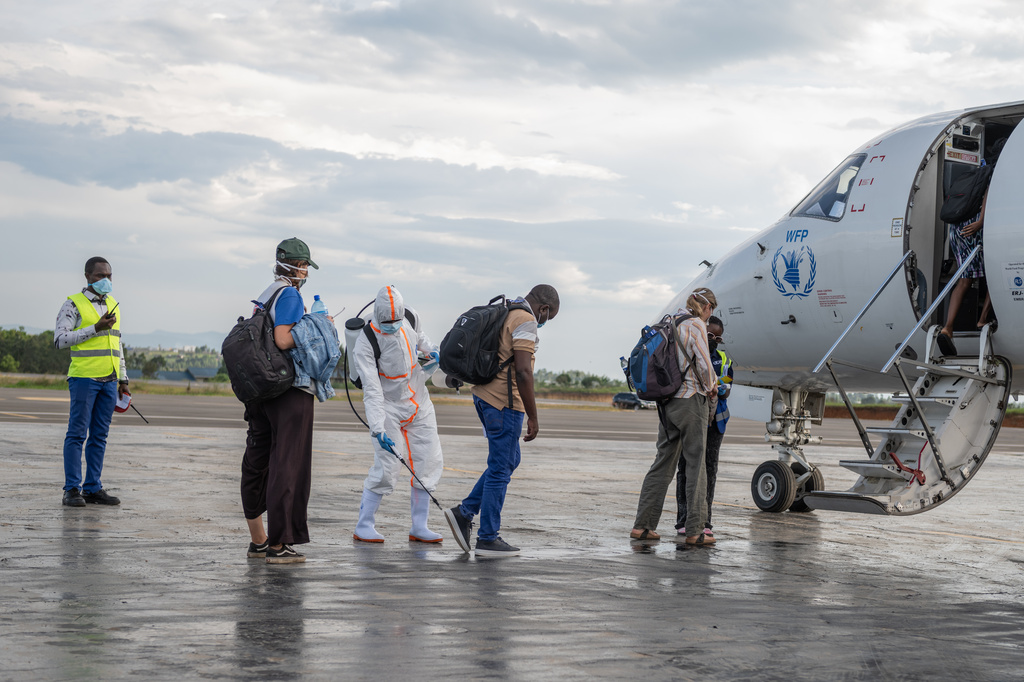 A health worker disinfects passengers prior to their boarding of the World Food Programme's (WFP) aircraft following the government's announcement of Bunia National Airport's reopening in Bunia, Congo, Tuesday, June 2, 2026. (AP Photo/Moses Sawasawa)