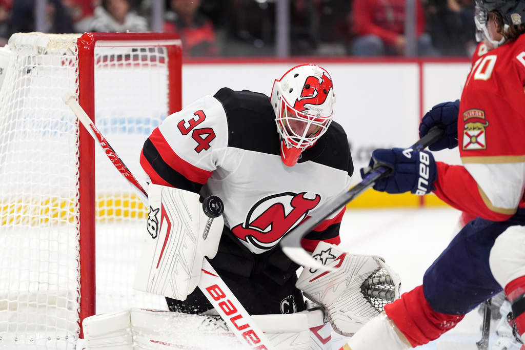 New Jersey Devils goaltender Jake Allen (34) deflects the puck under pressure from Florida Panthers center Jesper Boqvist (70) during the second period of an NHL hockey game, Thursday, Nov. 20, 2025, in Sunrise, Fla. (AP Photo/Rebecca Blackwell)