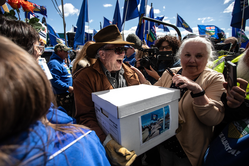 Supporters carry boxes of signatures to submit for a separation referendum to Elections Alberta in Edmonton, on Monday, May 4, 2026. (Jason Franson/The Canadian Press via AP)