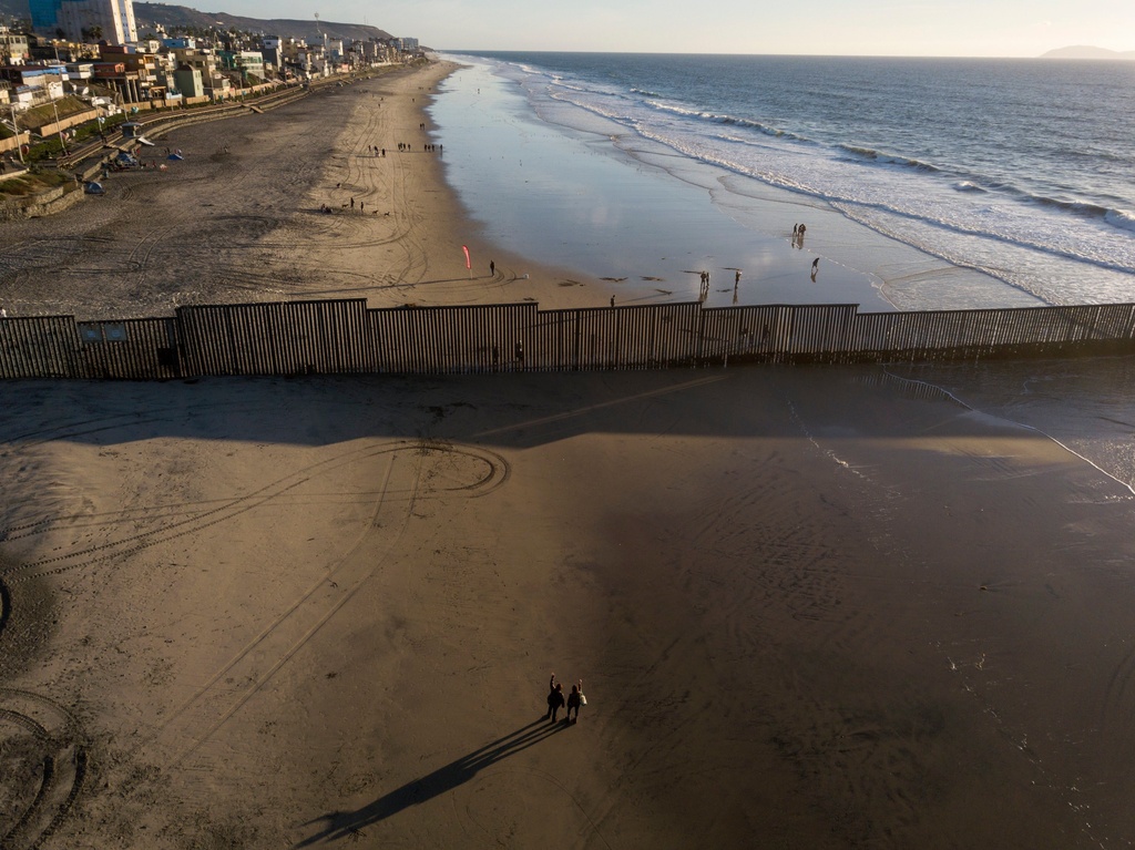 FILE - People in San Diego wave across the border structure to others in Tijuana, Mexico, Nov. 23, 2018. (AP Photo/Rodrigo Abd, File)