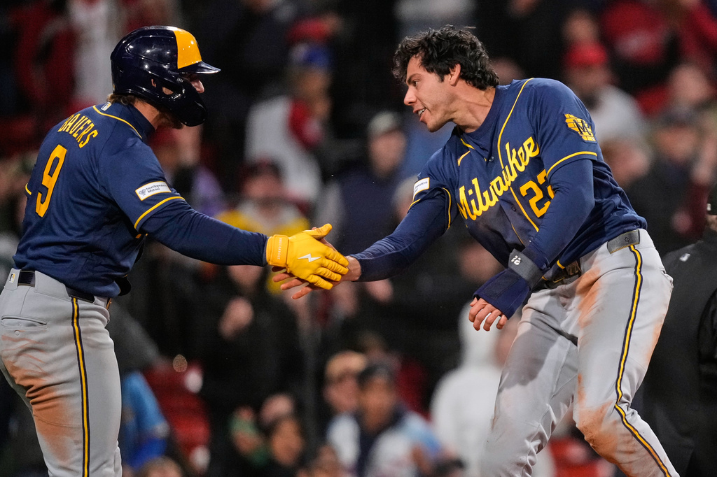 Milwaukee Brewers' Christian Yelich, right, is congratulated by Jake Bauers (9) after scoring on a single by Garrett Mitchell during the eighth inning of a baseball game against the Boston Red Sox at Fenway Park, Monday, April 6, 2026, in Boston. (AP Photo/Charles Krupa)