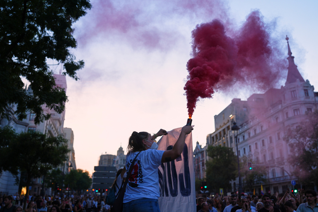 A woman holds a flare during a protest following the eviction last Wednesday of 87-year-old Maricarmen to demand stronger laws to protect renters at Puerta del Sol in Madrid, Spain, Saturday, Sept. 26, 2026. (AP Photo/Manu Fernandez)