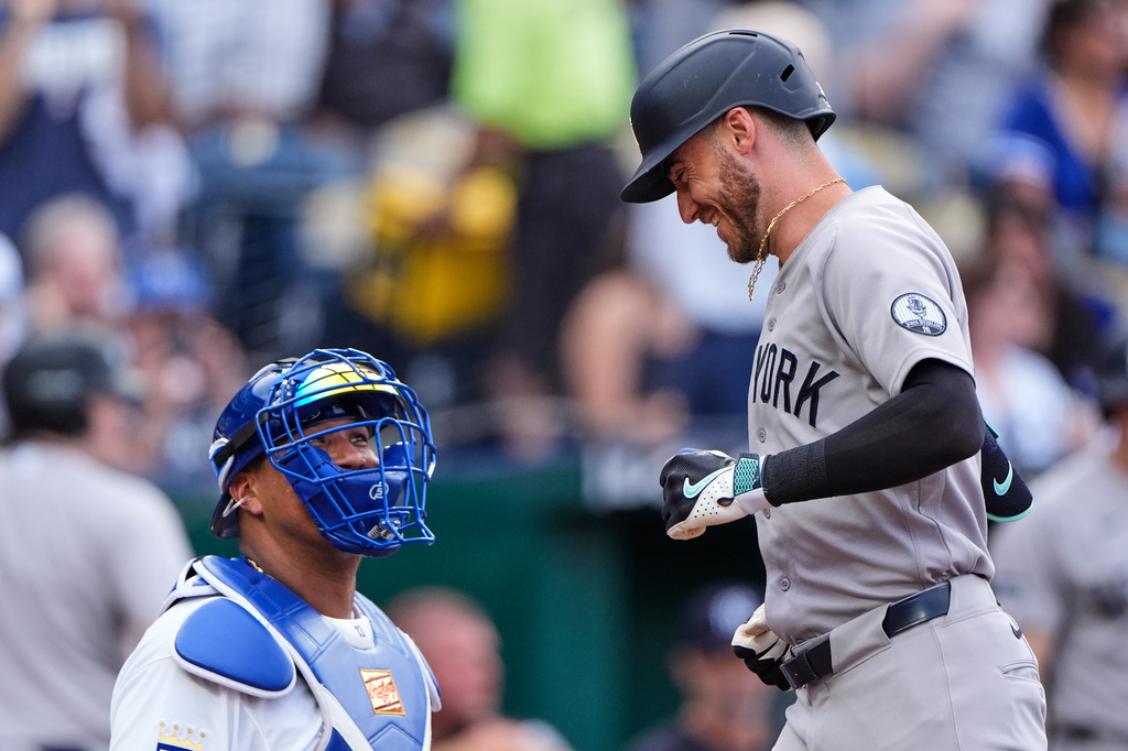 New York Yankees' Cody Bellinger runs past Kansas City Royals catcher Salvador Perez to score after hitting a solo home run during the first inning of baseball game, Tuesday, May 26, 2026, in Kansas City, Mo. (AP Photo/Charlie Riedel)