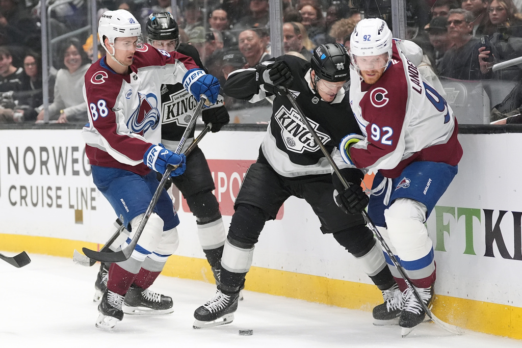 Colorado Avalanche's Gabriel Landeskog (92) and Martin Necas (88) battle Los Angeles Kings' Mikey Anderson (44) for the puck during the first period of Game 4 in the first round of an NHL hockey Stanley Cup playoff series Sunday, April 26, 2026, in Los Angeles. (AP Photo/Scott Strazzante)
