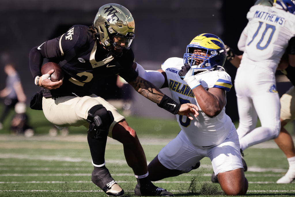 Wake Forest's Robby Ashford (2) avoids the tackle of Delaware's Ethan Saunders (8) during the first half of an NCAA football game, Saturday, Nov. 22, 2025, in Winston-Salem, N.C. (Allison Lee Isley/The Winston-Salem Journal via AP)