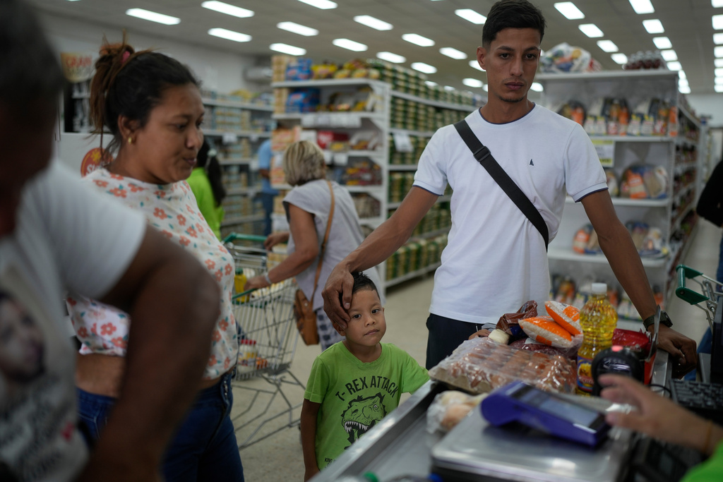 Mariela Gómez, her partner Abraham Castro, and her son Mathias, a Venezuelan migrant family who abandoned their journey to the United States and returned home following President Donald Trump's immigration crackdown, buy groceries for Christmas dinner in Maracay, Venezuela, Wednesday, Dec. 24, 2025. (AP Photo/Matias Delacroix)