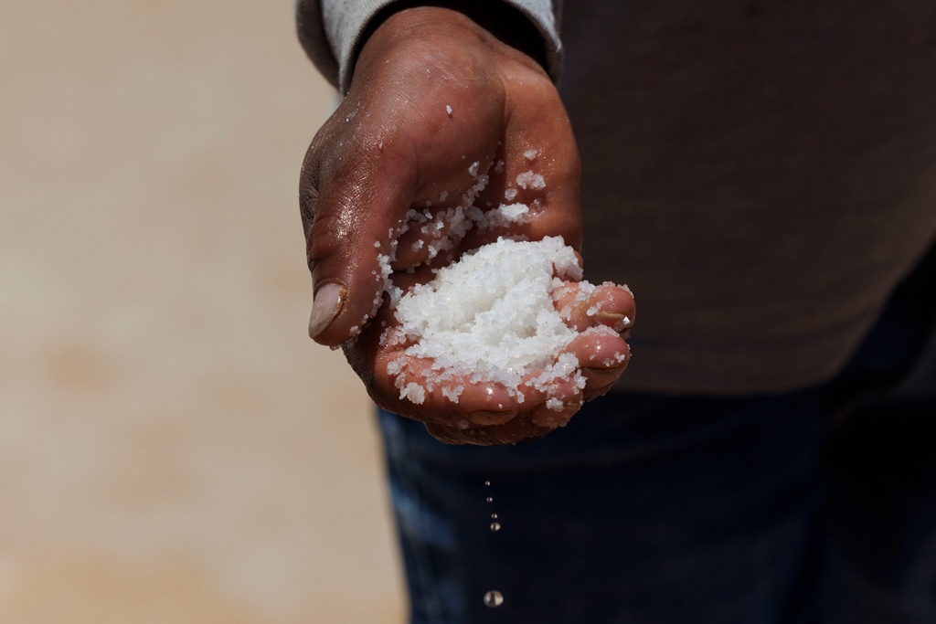 Uriel inspects the salt from one of his family's salt ponds at Salineras de Maras, Maras salt mines, in the Sacred Valley, near Cusco, Peru on Sunday, Aug. 31, 2025. (AP Photo/Alie Skowronski)