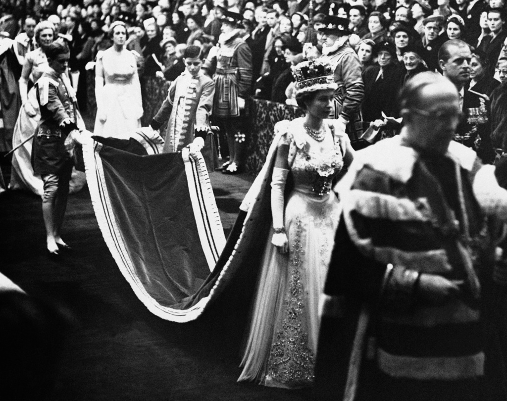 FILE - Queen Elizabeth II, wearing the imperial crown, walks through Royal gallery to the House of Lords chamber to officiate the opening of a new session of British Parliament in London, Nov. 30, 1954. (AP Photo, File)