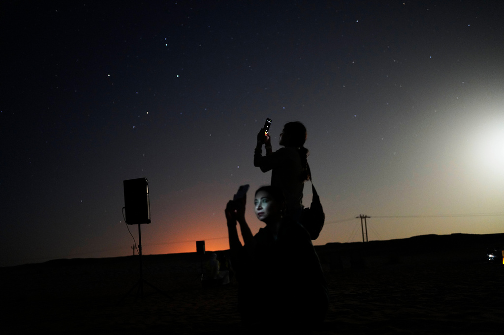This long-exposure photograph shows women taking mobile phone pictures in the Al Quaa Desert outside of Abu Dhabi, United Arab Emirates, Saturday, May 23, 2026. (AP Photo/Jon Gambrell)