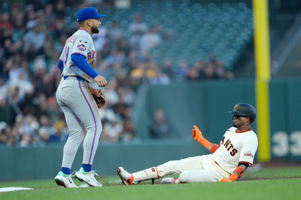 San Francisco Giants' Luis Arraez slides into third base in front of New York Mets third baseman Bo Bichette, left, after hitting a RBI triple during the first inning of a baseball game in San Francisco, Thursday, April 2, 2026. (AP Photo/Tony Avelar)