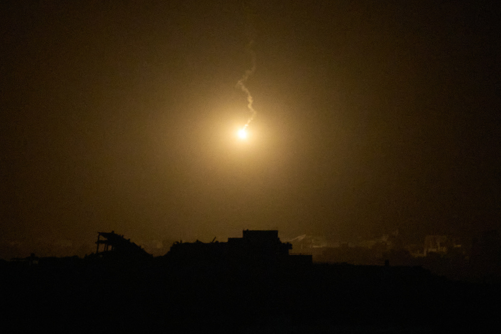 An Israeli army flare drifts over buildings destroyed during Israeli ground and air operations in the northern Gaza Strip, as seen from southern Israel, Thursday, Sept. 25, 2025. (AP Photo/Leo Correa)