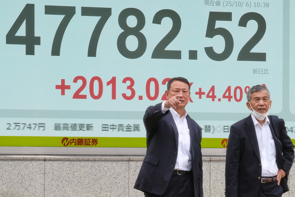 People stand in front of an electronic stock board showing Japan's Nikkei index at a securities firm Monday, Oct. 6, 2025, in Tokyo. (AP Photo/Eugene Hoshiko)