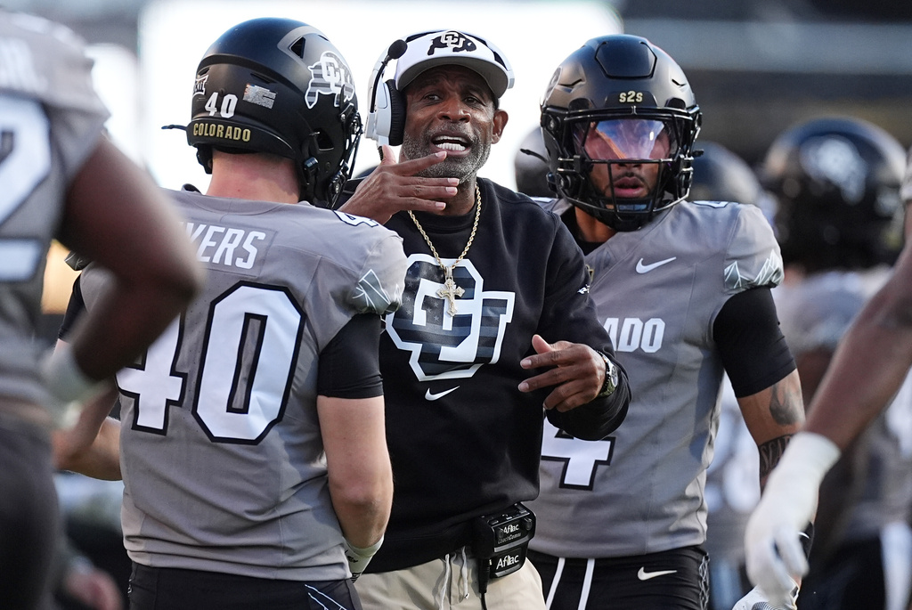 Colorado head coach Deion Sanders, center, confers with linebacker Shaun Myers, front, as cornerback Preston Hodge looks on in the first half of an NCAA college football game against Arizona, Saturday, Nov. 1, 2025, in Boulder, Colo. (AP Photo/David Zalubowski)