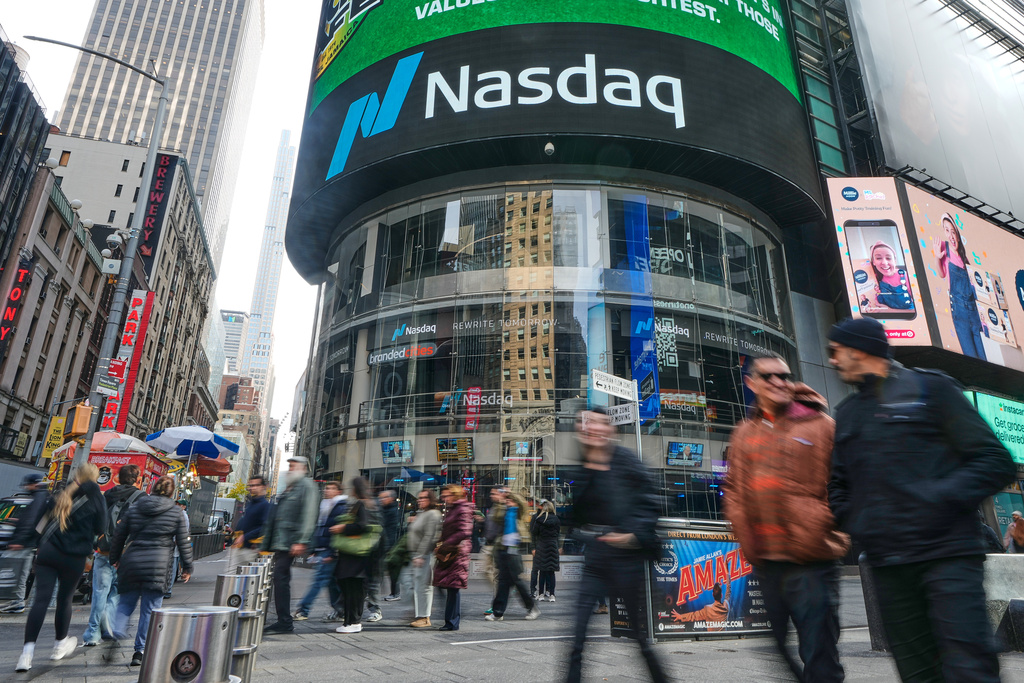 People pass the Nasdaq MarketSite in New York's Times Square, Friday, Nov. 7, 2025. (AP Photo/Richard Drew)