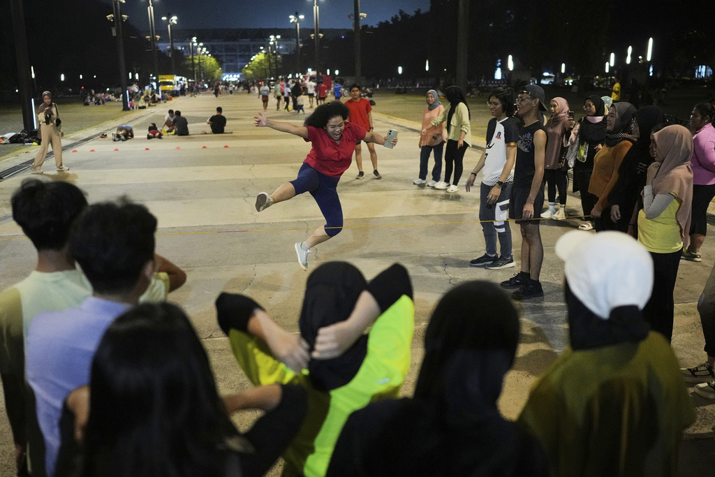 A participant jumps over a rubber rope during a community playing gathering in Jakarta, Indonesia, Friday, July 11, 2025. (AP Photo/Dita Alangkara)