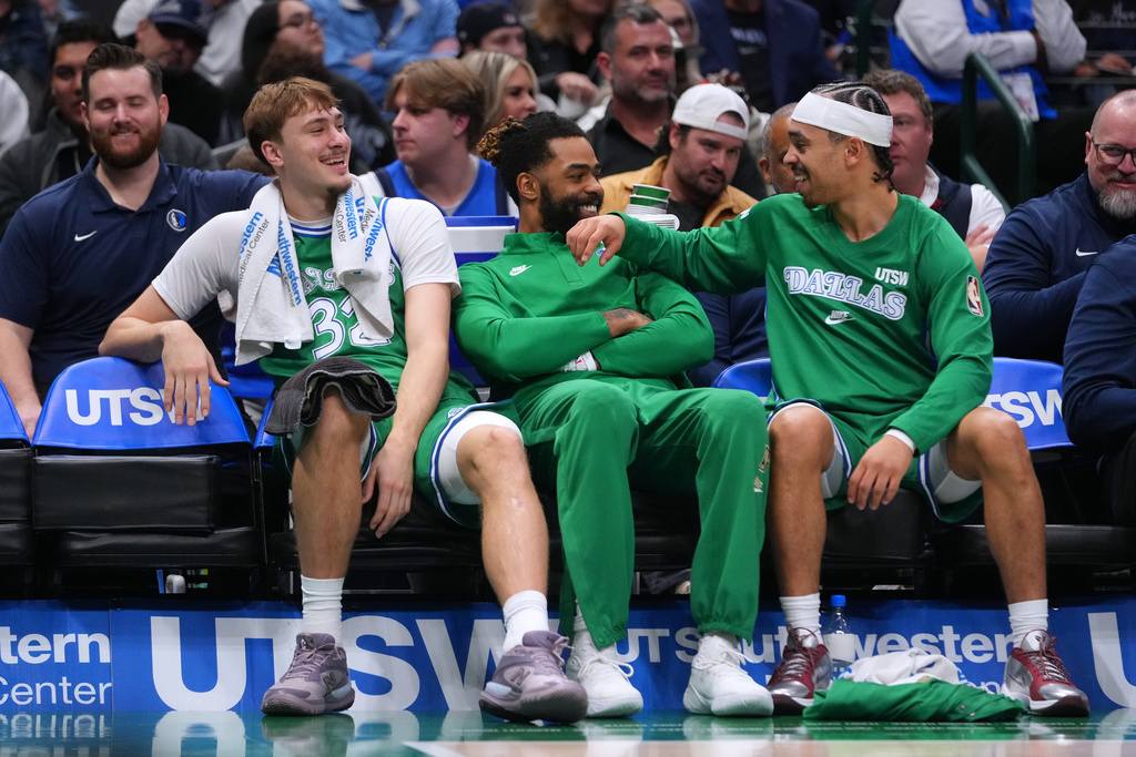 Dallas Mavericks forward Cooper Flagg, left, guard D'Angelo Russell, center, and guard Ryan Nembhard react on the bench during the first half of an NBA basketball game against the Brooklyn Nets Monday, Jan. 12, 2026, in Dallas. (AP Photo/Julio Cortez)
