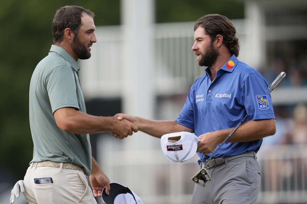 Scottie Scheffler speaks with Cameron Young on the 18th green during the final round of the Tour Championship golf tournament, Sunday, Aug. 24, 2025, in Atlanta. (AP Photo/Mike Stewart)