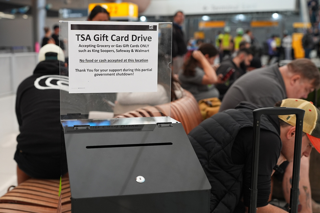 A collection box for gift card donations for TSA workers who have gone unpaid for several weeks, sits near travellers in the main terminal of Denver International Airport Friday, March 20, 2026, in Denver. (AP Photo/David Zalubowski)