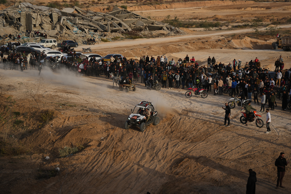 Palestinians watch youths riding their motorcycles and ATV on sand dunes in the Al-Zahra area, in the central Gaza Strip, Friday, Dec. 5, 2025. (AP Photo/Abdel Kareem Hana)