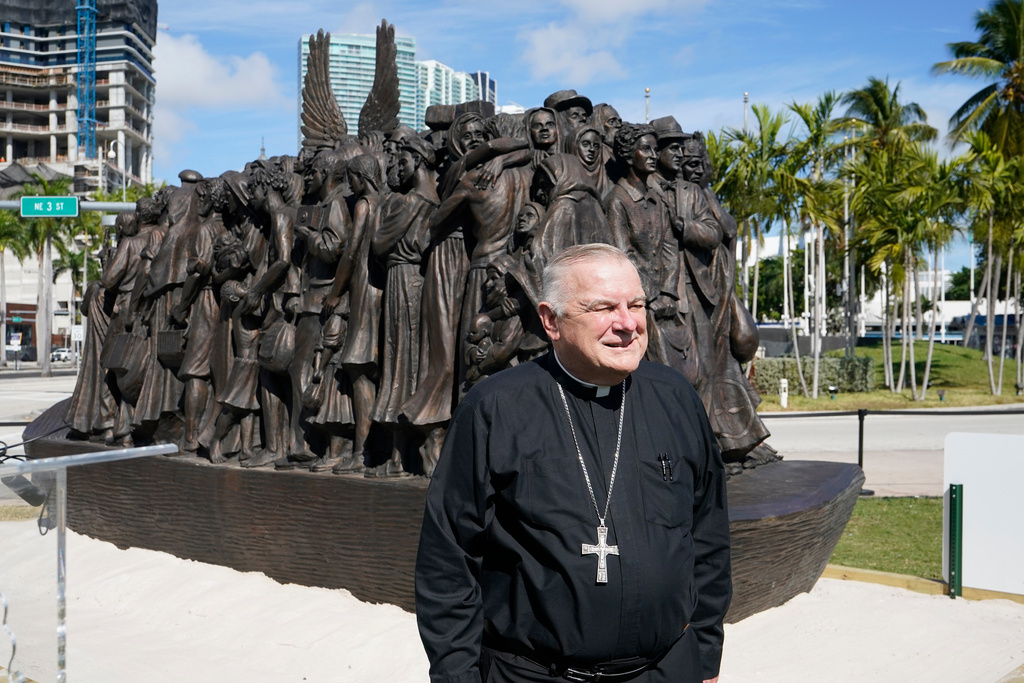 FILE - Archbishop of Miami Thomas Wenski poses in front of a traveling bronze sculpture titled "Angels Unawares," before blessing it, Feb. 10, 2021, in downtown Miami. (AP Photo/Wilfredo Lee, File)