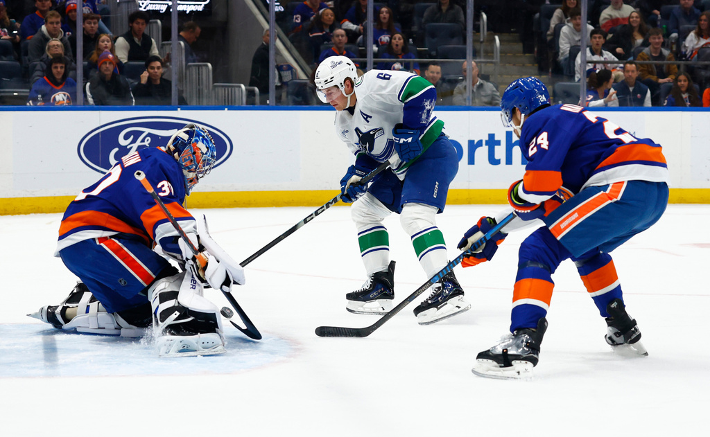 New York Islanders goaltender Ilya Sorokin, left, makes a save against Vancouver Canucks right wing Brock Boeser (6) during the first period of an NHL hockey game, Friday, Dec. 19, 2025, in Elmont, N.Y. (AP Photo/Noah K. Murray)