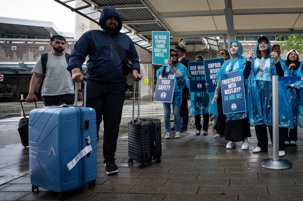 Viajeros pasan junto a personal de cabina de WestJet en huelga en el Aeropuerto Internacional de Vancouver, el domingo 2 de agosto de 2026. (Ethan Cairns/The Canadian Press vía AP)