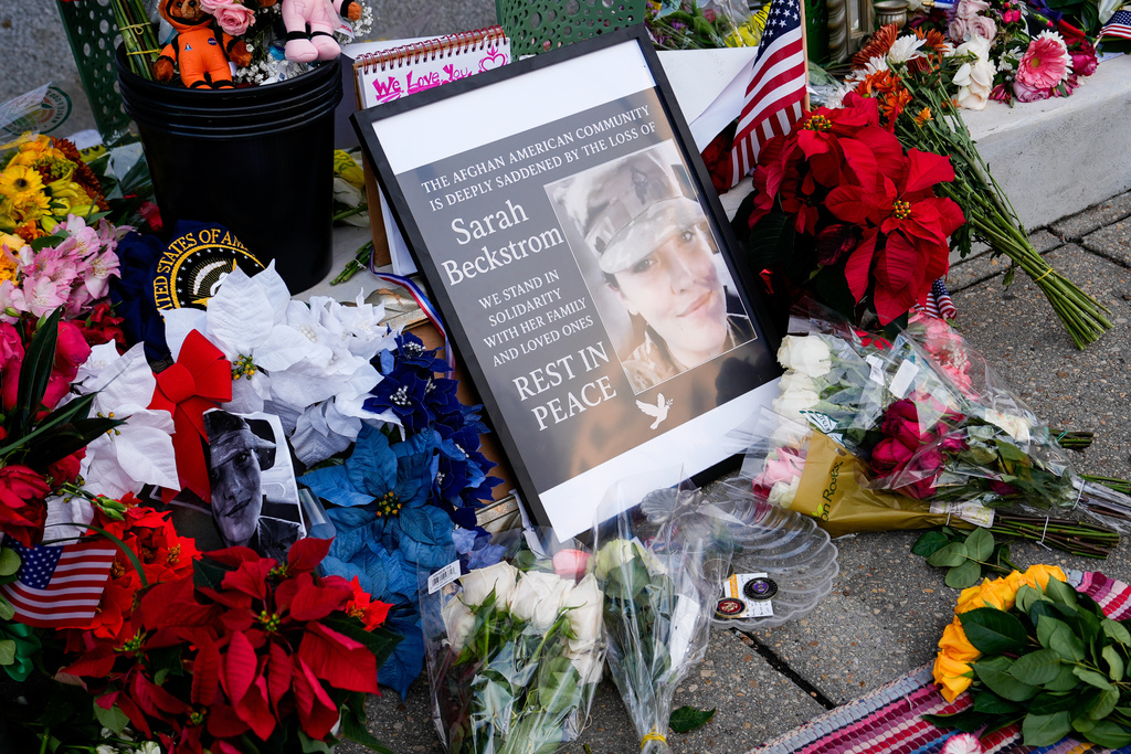 Flowers, challenge coins and other items lay near a photograph of U.S. Army Spc. Sarah Beckstrom at a makeshift memorial outside of Farragut West Station, near the site where two National Guard members were shot, Monday, Dec. 1, 2025, in Washington. (AP Photo/Julia Demaree Nikhinson)