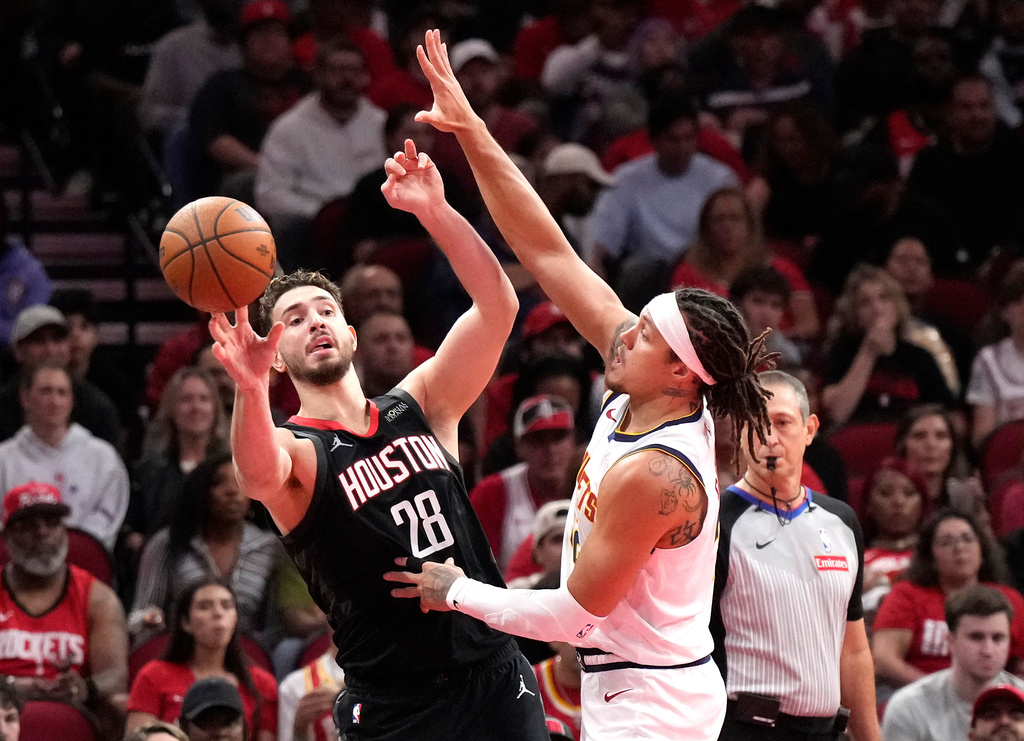 Houston Rockets center Alperen Sengun (28) passes the ball against Denver Nuggets forward Aaron Gordon during the first half of an NBA Cup basketball game, Friday, Nov. 21, 2025, in Houston. (AP Photo/Karen Warren)
