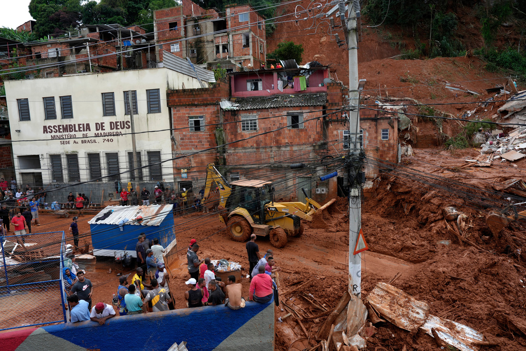 Firefighters and civil defense workers help at the site where homes collapsed due to heavy rains and severe flooding in the Parque Burnier neighborhood of Juiz de Fora in Minas Gerais state, Brazil, Tuesday, Feb. 24, 2026. (AP Photo/Silvia Izquierdo)