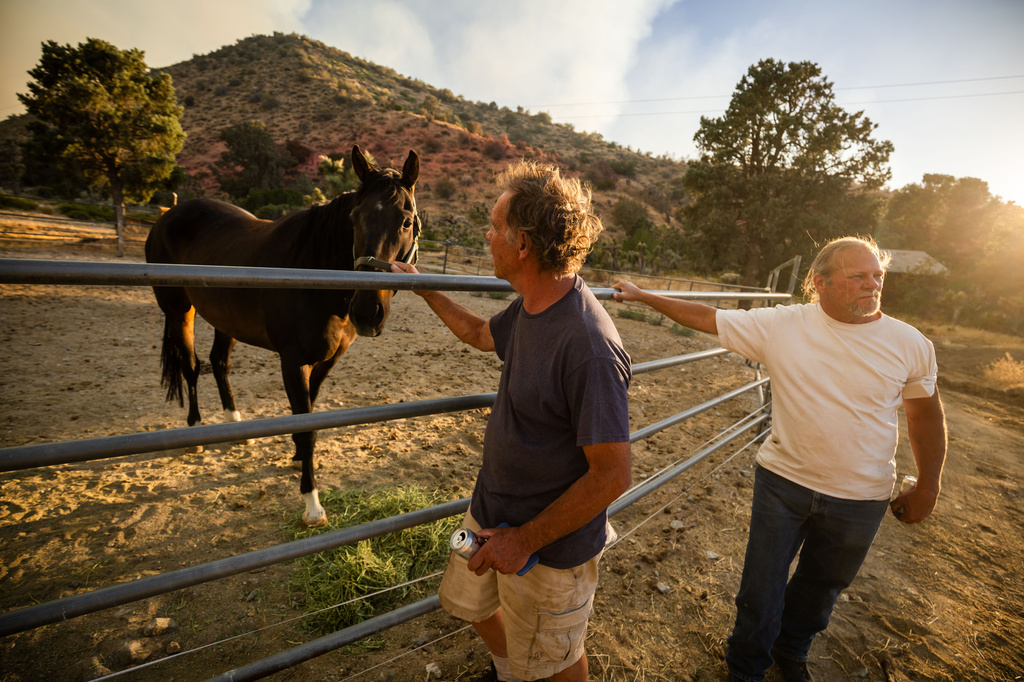 Alan Hiiesalu, a property owner at left, stays with his horse before surveying his land during the Summit Fire in Llano, CA. Friday, July 10, 2026. (AP Photo/Ethan Swope)